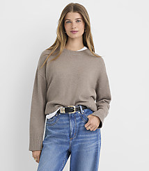 A woman in a beige sweater and blue jeans stands against a plain white background. carousel Product Image 2