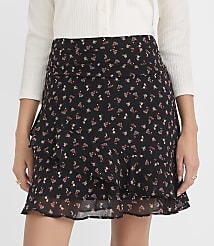 A woman in a black floral mini skirt with ruffles stands against a plain white background. carousel Product Image 2