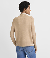 A woman in a tan mock-neck sweater and blue jeans stands against a plain, light gray background. carousel Product Image 3