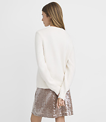 A woman in a cream sweater and sequined skirt stands against a plain white background. carousel Product Image 3