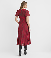 A woman in a red patterned dress and black boots stands against a plain white background. carousel Product Image 3