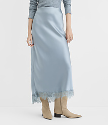 A woman in a light blue satin slip skirt with lace trim and beige boots stands against a plain white background. carousel Product Image 2