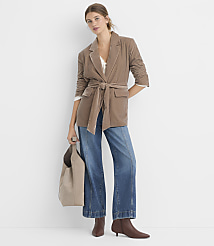 A woman in a brown belted blazer and wide-leg jeans stands against a plain white background, holding a taupe tote bag. carousel Product Image 2
