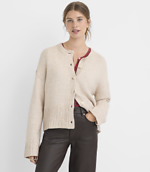 A woman in a beige cardigan and dark pants stands against a plain white background. carousel Product Image 1