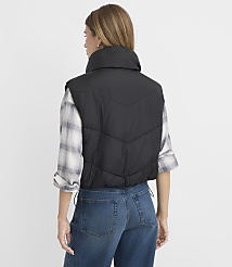 A woman in a black puffer vest and plaid shirt stands against a plain white background. carousel Product Image 3