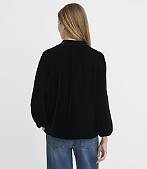A woman in a black velvet blouse and blue jeans stands against a plain white background. carousel Product Image 3
