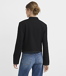 A woman in a black jacket and blue jeans stands against a plain white background. carousel Product Image 3