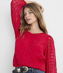 A woman in a red, sheer, plaid blouse with her hand behind her head stands against a plain gray background. carousel Product Image 2