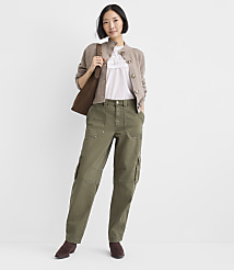 A woman wearing a beige cardigan, white lace top, and olive green cargo pants stands against a plain white background. carousel Product Image 1