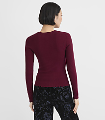 A woman wearing a burgundy long-sleeved top and floral black pants stands with her back to the camera against a plain white background. carousel Product Image 3