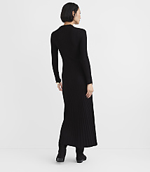 A woman wearing a long-sleeved black ribbed knit dress and black boots stands against a plain white background. carousel Product Image 3