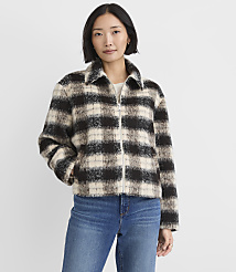 A woman wearing a black and white plaid jacket and blue jeans stands against a plain white background. carousel Product Image 2
