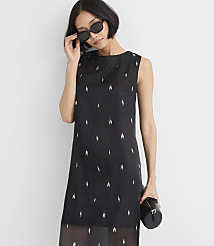 A woman wearing sunglasses and a black sleeveless dress with silver embellishments stands against a plain white background. carousel Product Image 2