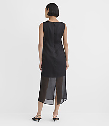 A woman wearing a sleeveless black dress with a sheer hem and black heels stands against a plain white background. carousel Product Image 3