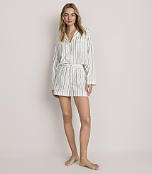 A woman wearing white and black striped pajamas stands against a plain, light-colored background. carousel Product Image 1