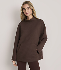 A blonde woman wearing a brown textured oversized tunic and leggings stands against a plain light-colored background. carousel Product Image 2
