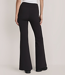 A person wears black flared trousers and a white top against a plain, light-colored background. carousel Product Image 3