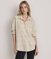 A woman wearing a beige plaid button-down shirt and black pants stands against a plain, light-colored background. carousel Product Image 1
