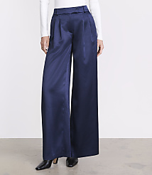 A person wears wide-leg navy blue trousers, a white long-sleeved top, and black pointed heels against a plain white background. carousel Product Image 2