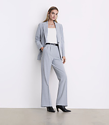 A woman wearing a light blue pinstripe suit and black heels stands against a plain white wall. carousel Product Image 1