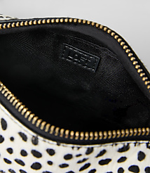 A white and black spotted pouch with a gold zipper and black interior is set against a plain light gray background. carousel Product Image 2
