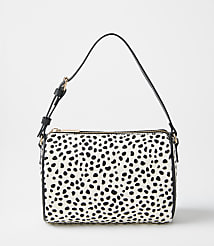 A white and black spotted handbag with a black strap sits against a plain, light gray background. carousel Product Image 3