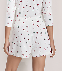 A person wears a white pajama set with a small red floral print against a plain, light-colored wall. carousel Product Image 3
