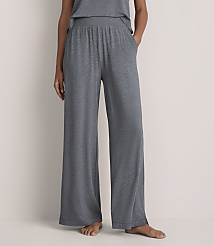 A person wearing wide-leg grey lounge pants stands against a plain, light-colored wall. carousel Product Image 2
