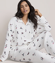 A woman wearing white cat-patterned pajamas sits against a plain, light-colored background. carousel Product Image 1