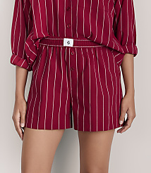 A person wears a red and white striped pajama set against a plain light gray background. carousel Product Image 2