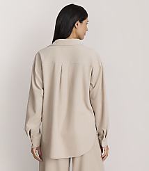 A woman stands with her back to the camera wearing a beige oversized button-down shirt and matching trousers against a plain light-colored background. carousel Product Image 3