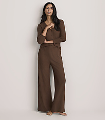 A woman wearing a brown ribbed knit two-piece set stands against a plain, light-colored wall. carousel Product Image 1