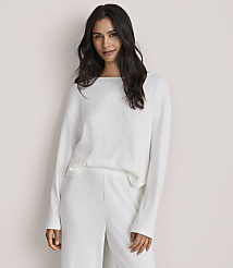 A woman with long dark hair wearing a white ribbed two-piece set stands against a plain, light-colored background. carousel Product Image 2