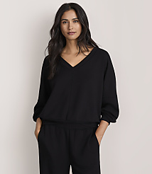 A woman wearing a black v-neck top and matching pants stands against a plain, light-colored background. carousel Product Image 1