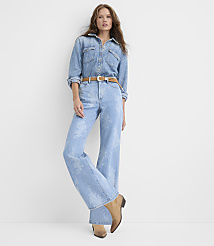 A woman wearing a light-wash denim shirt and matching wide-leg jeans with a brown belt stands against a plain white background. carousel Product Image 1