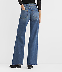 A person wearing a black top, wide-leg blue jeans, and black shoes stands against a plain white background. carousel Product Image 3