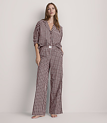 A woman stands in a light-colored room wearing a black and white checkered pajama set, with her hands in her pockets. carousel Product Image 1