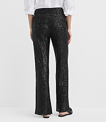 A person stands with their back to the camera wearing a white blouse and black sequined trousers against a plain white background. carousel Product Image 3