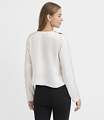 A woman wearing a white long-sleeved blouse and black pants stands with her back to the viewer against a plain white background. carousel Product Image 3