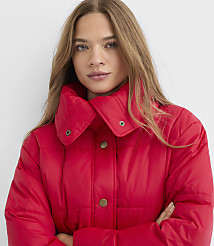 A woman with long brown hair wearing a bright red puffer jacket stands against a plain white background. carousel Product Image 4