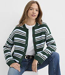 A woman wearing a striped green cardigan and blue jeans sits against a plain white background. carousel Product Image 1