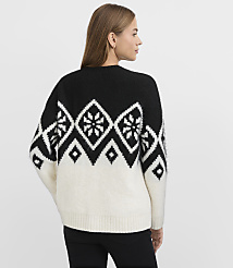A woman wearing a black and white patterned sweater and black pants stands against a plain white background. carousel Product Image 4