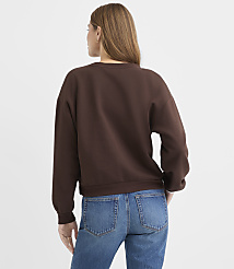 A woman wearing a brown sweatshirt and blue jeans stands with her back to the camera against a plain white background. carousel Product Image 3