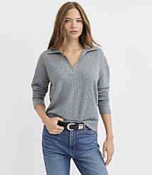 A woman wearing a grey ribbed collared top and blue jeans stands against a plain white background. carousel Product Image 2