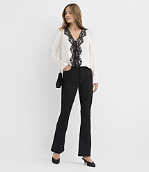 A woman wearing a white lace-trimmed blouse and black flared trousers stands against a plain white background. carousel Product Image 2