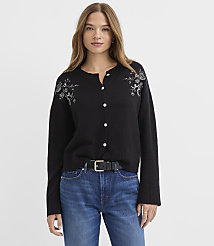 A woman wearing a black embroidered cardigan and blue jeans stands against a plain white background. carousel Product Image 2