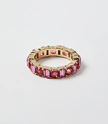 A gold ring set with pink gemstones rests on a plain white background. carousel Product Image 1