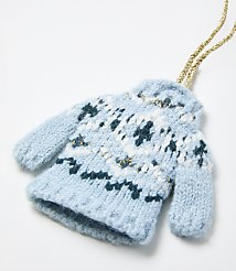 A small, knitted light blue mitten with white and dark blue patterns and a gold string sits against a plain white background. carousel Product Image 2