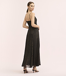 A woman wearing a long, leopard-print black dress and high-heeled sandals stands against a plain, light pink background. carousel Product Image 3