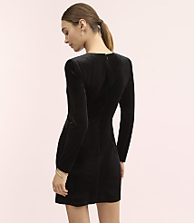 A woman wearing a black velvet long-sleeved mini dress stands against a plain light pink background. carousel Product Image 3